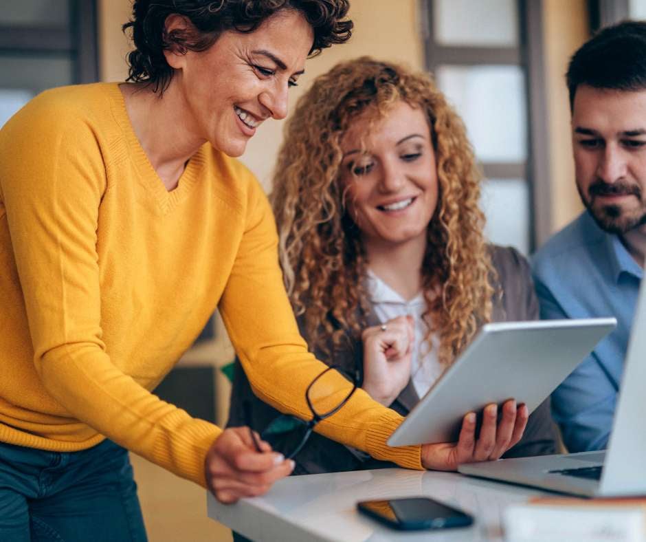 A team of professionals engaging with a digital tablet, reflecting the collaborative effort in crafting customized IT solutions tailored to unique business needs by Fluid IT.