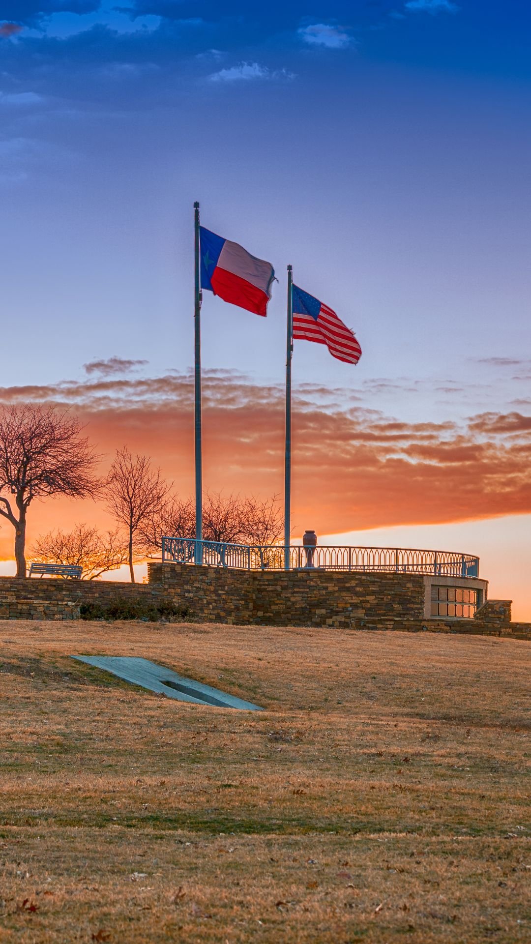 The Texas and United States flags flying at dusk, symbolizing Fluid IT's commitment to local data security and recovery services in Frisco, Texas.