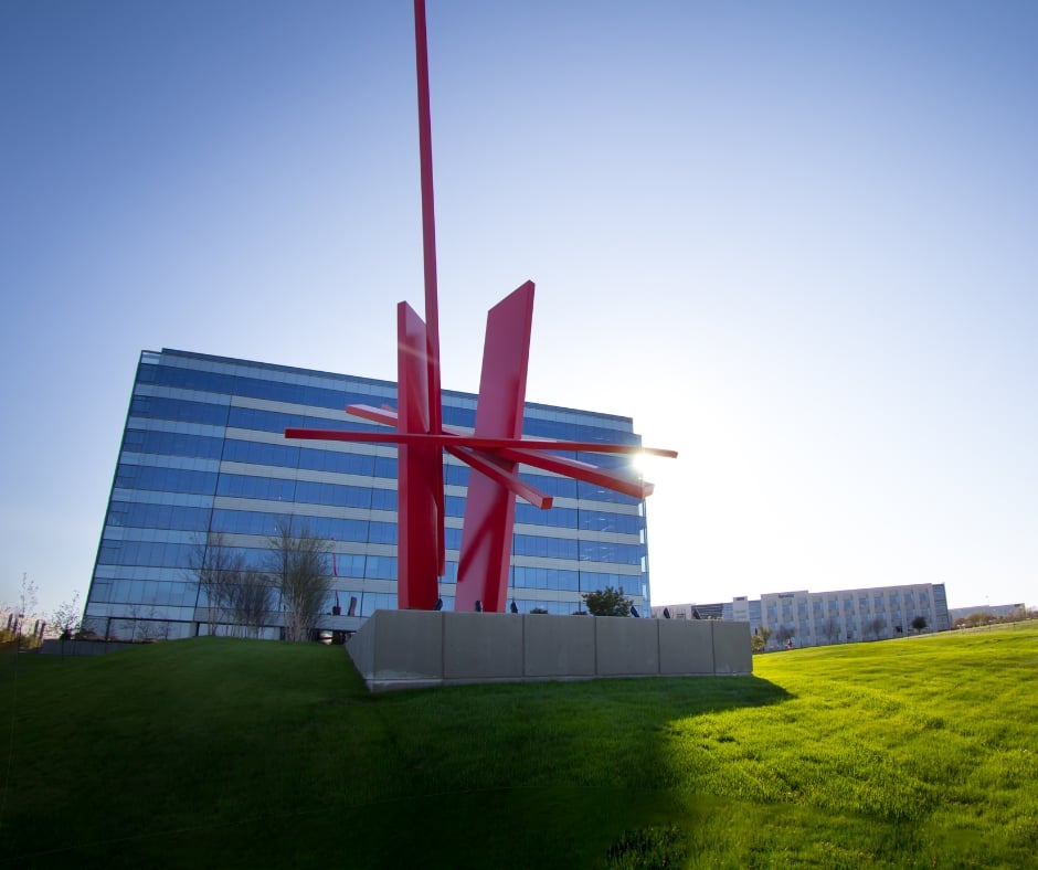 Contemporary red sculpture in front of a modern office building in Frisco, symbolizing the innovative and secure digital solutions provided by Fluid IT.
