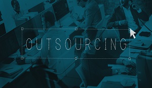 The word Outsourcing written on the poster of people working on their workstation in office.