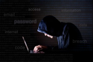 An anonymous man with a black hoodie working on the latop- Hacking 